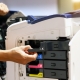 Technician hand open cover photocopier or photocopy to fix paper jam and replace ink cartridges for scanning fax or copy document in office workplace.